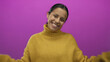 © Krakenimages.com - Hispanic woman smiling joyfully in a cozy yellow sweater with hands raised in excitement against a vibrant pink background, exuding happiness and positivity.
