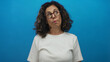 © Krakenimages.com - Middle aged hispanic woman puckers her lips to one side while tilting her head against a blue studio wall; playful silliness and amusement.