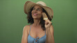 © Krakenimages.com - Woman enjoying ice cream while wearing a sunhat and swimsuit against a green background, conveying a relaxed vacation vibe.
