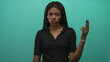 © Krakenimages.com - African american woman making ok sign with raised right hand, showing nose ring and braided hair in turquoise studio; indifference.