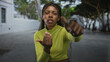 © Krakenimages.com - Woman with braided hair and serious expression pointing finger toward camera on street in lime green cropped top; confidence focus.