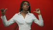 © Krakenimages.com - Woman pointing thumbs to chest while wearing glasses and white blouse in studio with red backdrop; confidence.