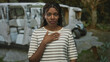 © Krakenimages.com - African american woman with hand on chest gesture in forest, striped shirt and ring visible; gratitude reflection.