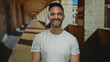 © Krakenimages.com - Young hispanic man smiling on university campus with old architecture in the background suggesting a lively academic environment.