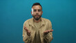 © Krakenimages.com - Young man pointing finger to camera with right hand wearing checked shirt in studio against teal backdrop; direct appeal confidence.