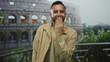 © Krakenimages.com - Man in front of coliseum building blows a kiss with hand to mouth while smiling at camera; friendly greeting joy.