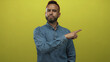 © Krakenimages.com - Man points finger at camera in yellow studio wearing denim shirt and visible beard; disapproval warning.