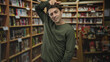 © Krakenimages.com - Man winking and making bunny ears with hand, visible face and green shirt in a bookstore building aisle; playful mischief.