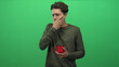 © Krakenimages.com - Man holding red mug and clutching chest with hand, wearing olive long sleeve shirt in studio green screen; discomfort vulnerability.