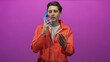 © Krakenimages.com - Man in orange prisoner jumpsuit holds blue telephone handset to ear and gestures with hand in studio; remorse reflection.