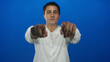 © Krakenimages.com - Young hispanic man pointing confidently at camera against blue background wall.