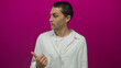 © Krakenimages.com - Young man in white shirt with thoughtful expression against pink background gestures with thumb over shoulder.