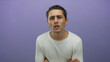 © Krakenimages.com - Young hispanic man in white shirt looks puzzled against an isolated purple background wall, capturing curiosity and intrigue.