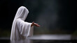 © Denis Yevtekhov - Faceless figure in white robes standing at the edge of dark water, arm extended forward in a gesture of welcome, defocused dark moody background behind, resurrection, salvation, hope, faith,