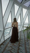 © Krakenimages.com - Woman with exposed back holding a cocktail and gazing through large windows on a cruise ship deck corridor; serenity.
