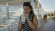 © Krakenimages.com - Woman sipping a pineapple cocktail on a cruise terrace, holding glass and straw with sunglasses on head; vacation relaxation.