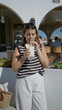 © Krakenimages.com - Woman holding cold drink with hands sips straw at bar counter in building under bright sunlight; summer relaxation.