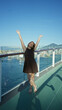 © Krakenimages.com - Woman with arms raised above head leaning on deck railing, smiling toward the sea; vacation joy.