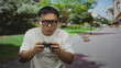 © Krakenimages.com - Chinese man holding game controller with focused expression playing video game on street; concentration.