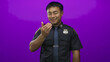 © Krakenimages.com - Young smiling chinese policeman wearing visible badge in dark uniform shows thumbs up gesture in purple studio; confidence.