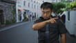 © Krakenimages.com - Chinese policeman pointing finger on grey street wearing badge and radio microphone under green trees; authority.