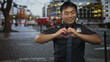 © Krakenimages.com - Young smiling man in police uniform forms heart shape with hands on rainy street; compassion caring generosity warmth.