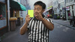 © Krakenimages.com - Man in striped referee shirt raises yellow card with whistle hanging from neck on city street; discipline.