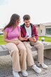 © Alejandro - Young adults using smartphones together on college campus
