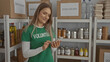 © Krakenimages.com - Woman volunteer using phone in charity center surrounded by donation boxes and supplies, conveying community support and care.