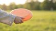 © Guillotine - Toddler holding orange frisbee in sunny park during springtime