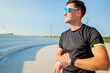 © muse studio - Man checks smartwatch during outdoor exercise session by arranged steps near a park on a bright sunny day