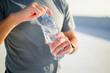 © muse studio - Person opens a water bottle under bright sunlight in an outdoor setting during the afternoon