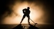 © kinomaster - A dynamic silhouette of a hockey player in action, highlighted by dramatic backlighting and misty atmosphere. Generative AI.