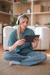 © Dexon Dee - Woman sitting on floor with headphones using tablet