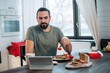 © Anna - A man is having breakfast at home with a tablet.