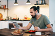 © Anna - A man is having breakfast at home with a tablet.