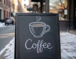 © Maria Iacubovscaia - A chalkboard sign displays a steaming cup of coffee in a winter street setting. Snow covers the ground, and buildings are visible in the background.