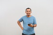 © ArvStd - Asian smiling man standing looking at camera, holding phone with hand. Isolated on white