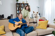 © Elena Medoks - Father playing guitar with daughter and dog at home