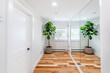 © nagelsphoto - Modern minimalist hallway interior with hardwood floor, mirrored closet doors and potted fiddle leaf fig plant in bright residential home corridor