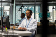 © DC Studio - Startup helpdesk admin in office speaking in headset microphone, responding to service alerts. African american IT specialist doing tech support, helping users across remote infrastructure