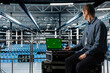 © DC Studio - Data center employee using green screen notebook, minimizing downtime through predictive maintenance. Engineer using mockup laptop in server hub, implementing sustainable energy efficient technologies