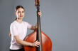 © New Africa - Girl playing double bass on grey background, space for text