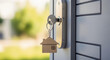 © Sulastri - Close-up of a house key with a house-shaped keychain in a door lock, symbolizing home ownership