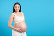 © New Africa - Pregnant woman touching her belly on light blue background, space for text