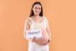 © New Africa - Pregnant woman holding card with word Name and question mark on orange background