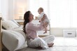 © New Africa - Smiling mother holding her cute baby near sofa on floor at home. Space for text