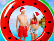 © New Africa - Happy couple with Santa hats and inflatable ring against sea resort