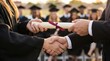 © Tanomsap - graduate receiving a diploma and shaking hands during a graduation ceremony. Academic achievement and educational success concept with students in caps and gowns blurred in the background.