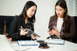 © laddawan - Asian women lawyers reviewing contract documents on tablet, discussing legal compliance, finance, cybersecurity and corporate business strategy